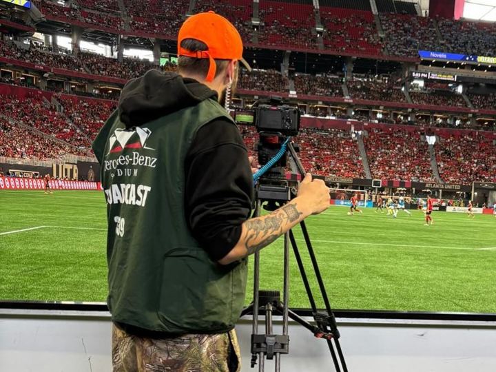 Operator in a hunting cap on the camera platform at a soccer match