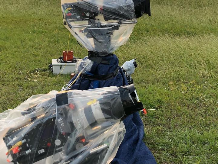 Remote camera wrapped in plastic on the grass near the pad