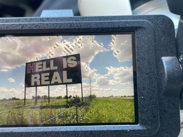 Hell Is Real billboard framed in a camera monitor