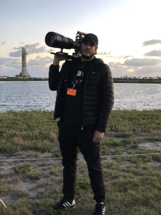 Operator with a long lens at the launch complex at dusk